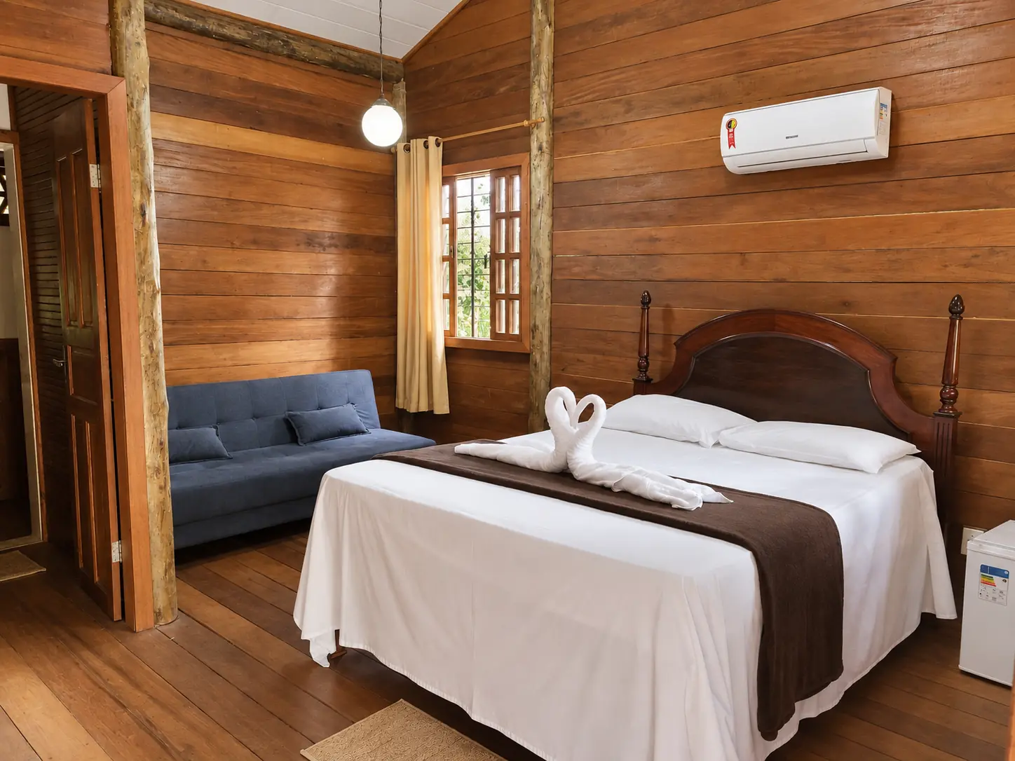 Chalé Premium do Acquamarine Park Hotel, com paredes de madeira, cama de casal, sofá e ar-condicionado