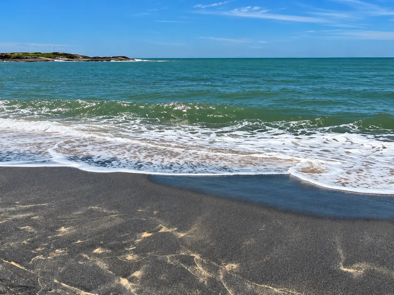 Faixa de areia monazítica escura na beira do mar, em Guarapari