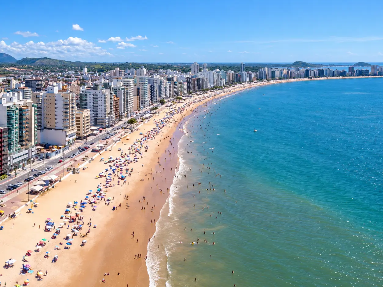 Vista aérea da Praia do Morro, em Guarapari, com a orla de prédios e o mar azul